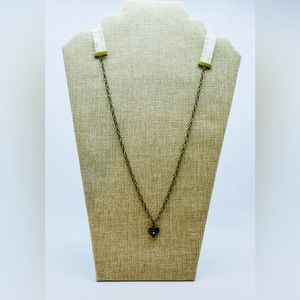 Small brass heart pendant with an elastic cream ribbon necklace.